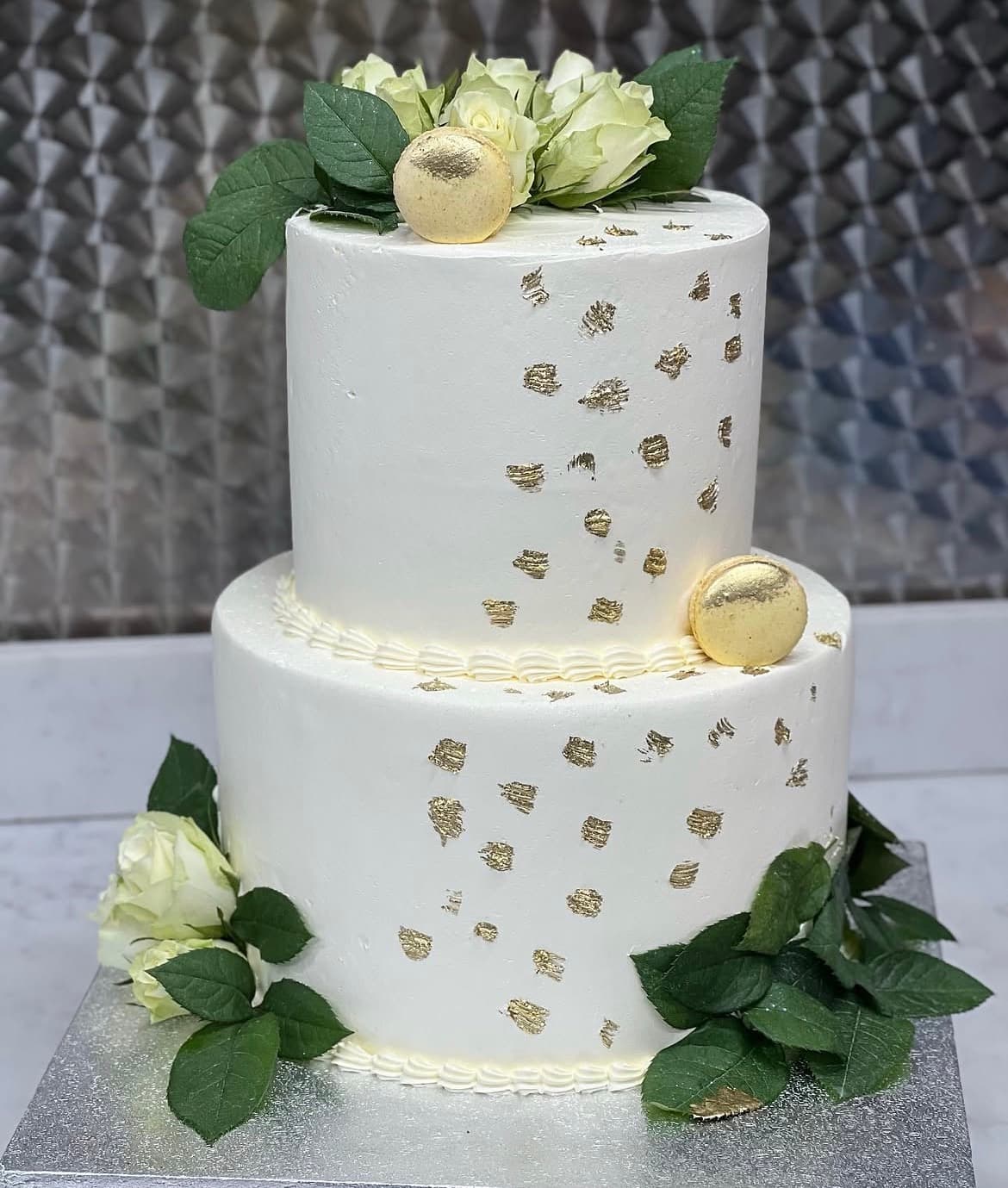 Tiered white cake with gold detailing and roses