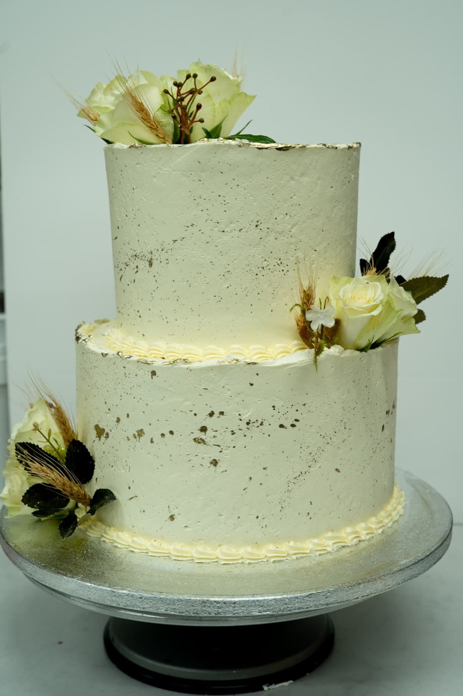 Two-tier cake with gold leaf detail and white roses